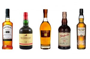 Five whisky bottles against a white background