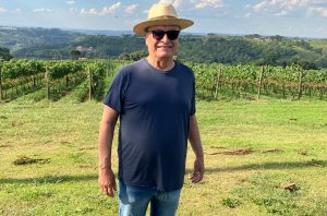 A man standing in a vineyard wearing a hat anad sunglasses