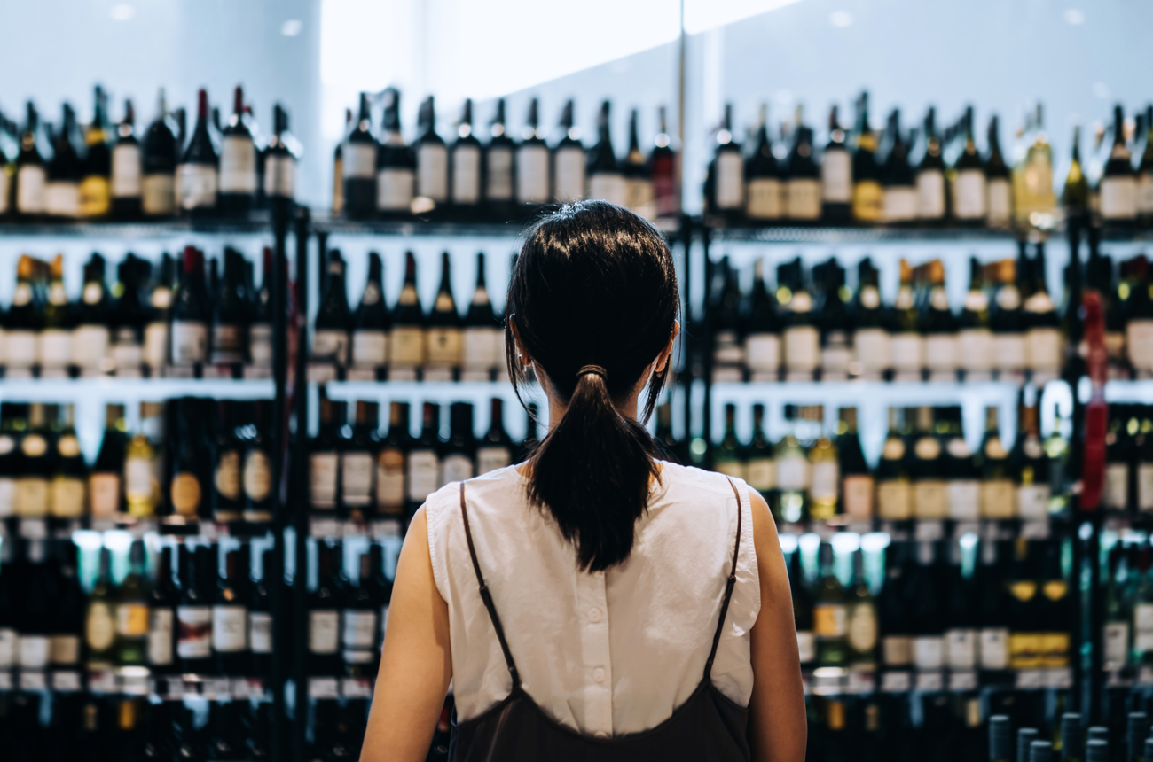 a woman shopping for wine is standing in front of a large selection of wines