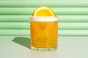 Orange cocktail against a green background