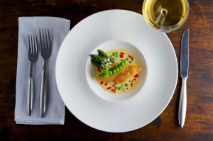 A dish of salmon with creamy sauce on a table with a glass of wine