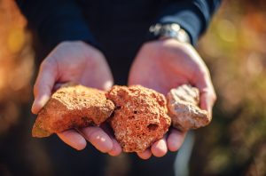 A pair of hands holding pumice-like volcanic rocks