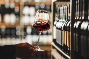 Hand holding glass of red wine in wine store