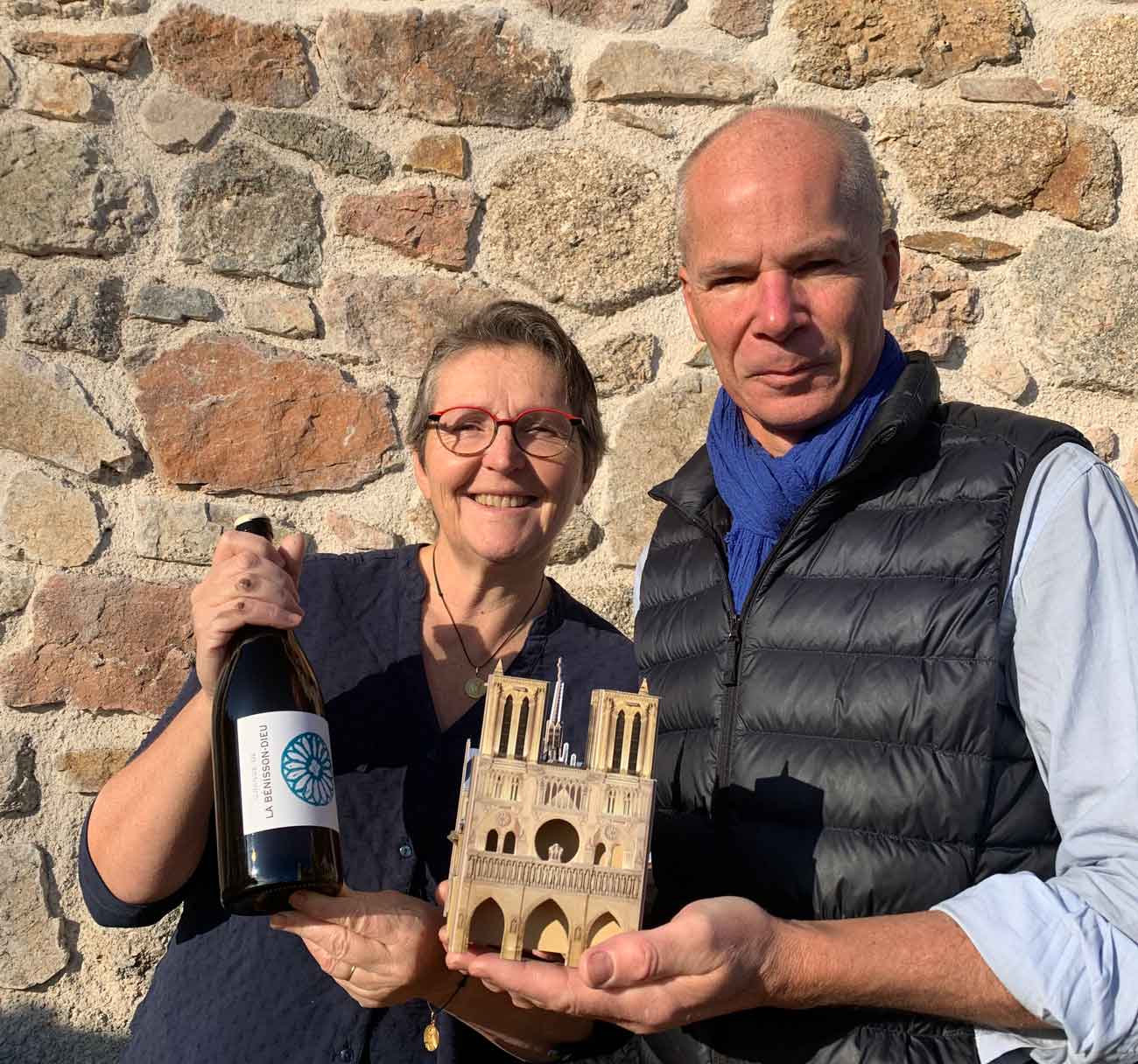 Régis and Aude-Reine Anouil with bottle of wine and model of Notre-Dame Cathedral