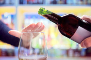 Hand indicating not to pour more wine into glass