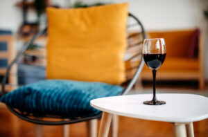 Glass of red wine on white table with out of focus chair in background