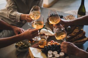 Four hands holding glasses of rosé with selection of food